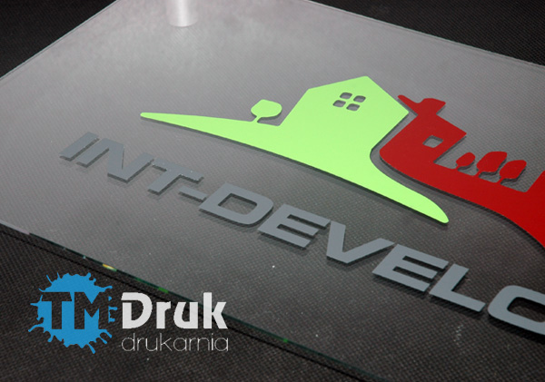Szyld reklamowy wykonany na przeźroczystej pleksi, z logo firmy wyklejonym z folii samoprzylepnej