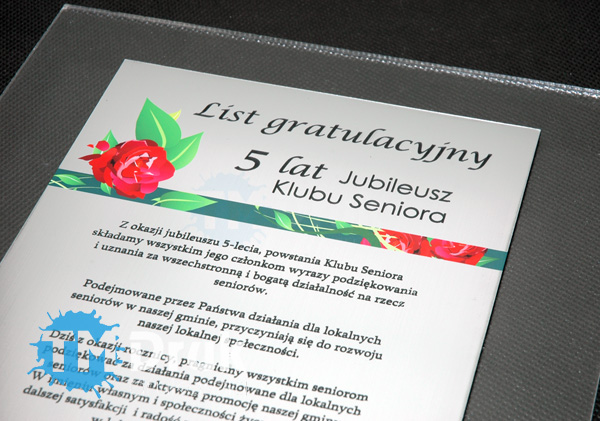 Realizacja podziękowania - listy gratulacyjnego z srebrego laminatu grawerskiego na bezbarwnym podkładzie z pleksy